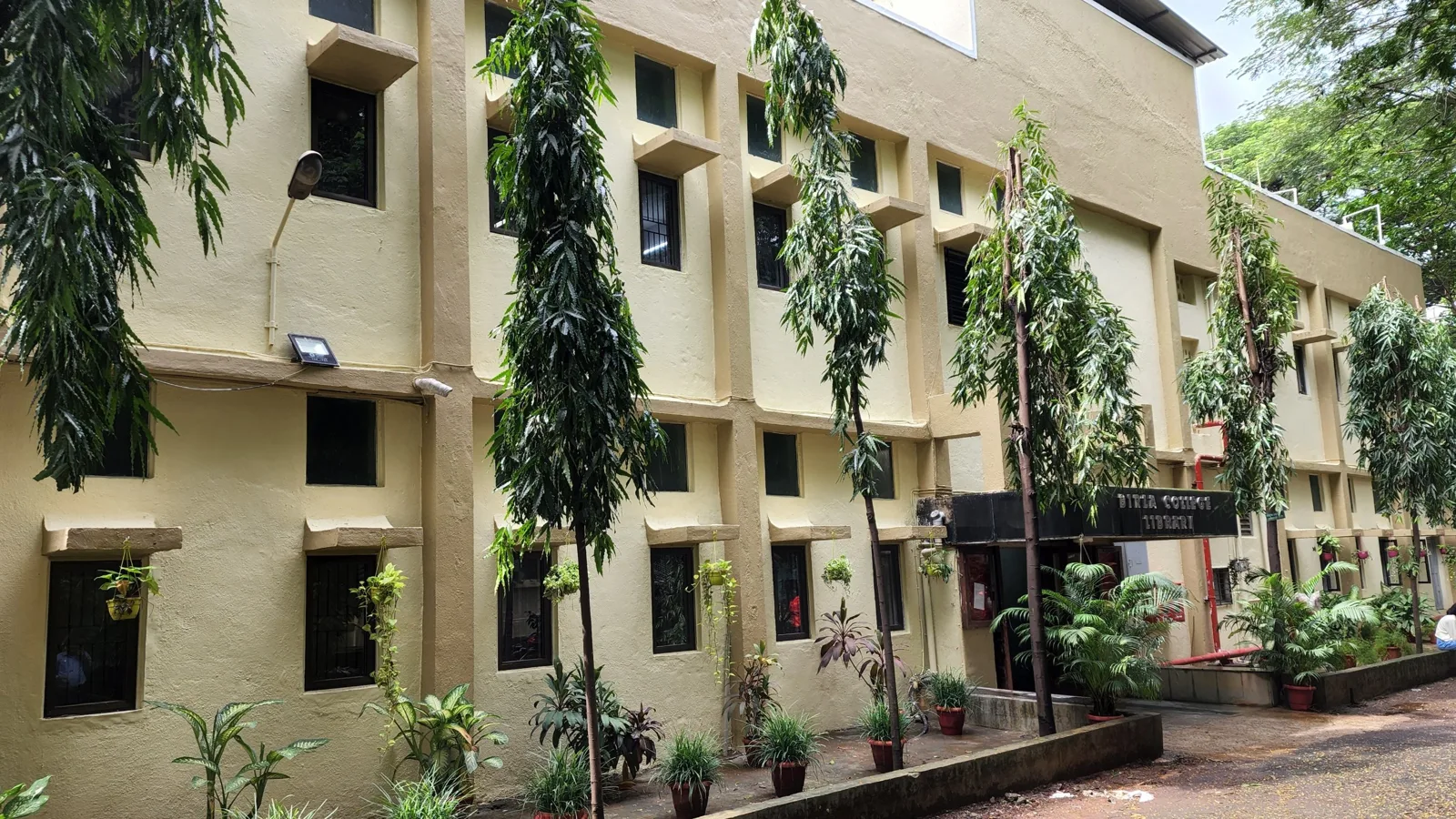 B. K. Birla College library building framed by mature trees